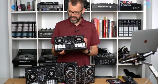 DJ examines several DJ controllers behind desk in DJ studio