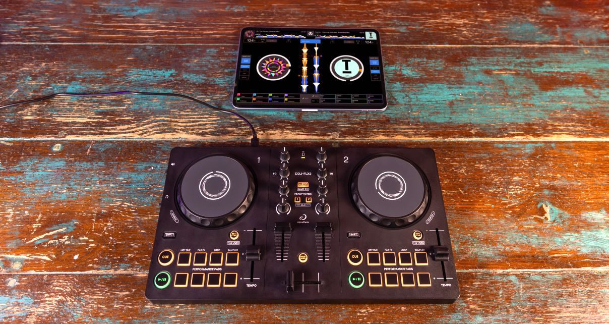 A DDJ-FLX2 controller and iPad lay flat on a weathered but colourful table. 