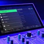 Close-up of a DJ controller screen displaying streaming options like Amazon Music, SoundCloud, and Tidal, with illuminated control knobs.