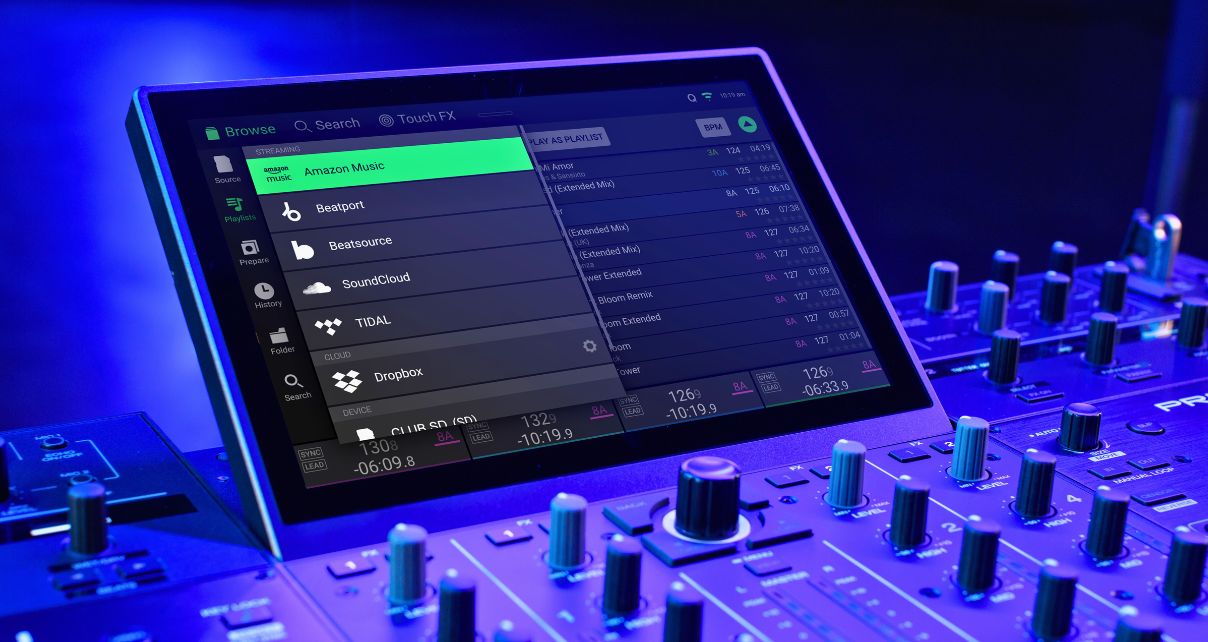 Close-up of a DJ controller screen displaying streaming options like Amazon Music, SoundCloud, and Tidal, with illuminated control knobs.