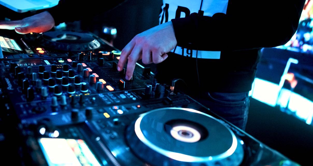A DJ mixing in a nightclub on pro DJ gear.