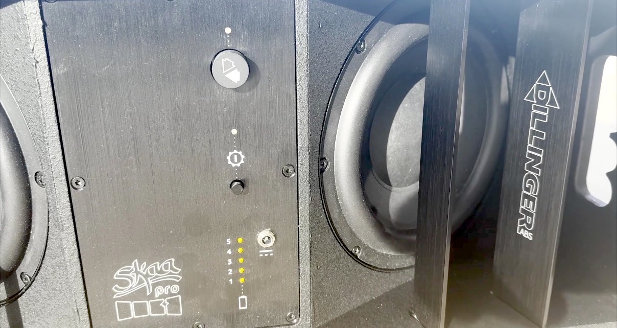 Close up view of a black Dillinger Labs Death From Below subwoofer with green LEDs lit to show battery life. 