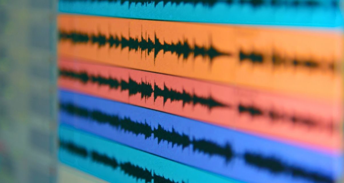 Close-up view of several stacked audio waveforms on a computer screen. Each waveform is represented in a different colour.