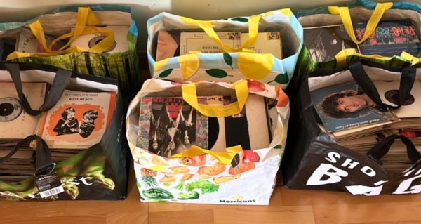 Top-down view of six tote bags filled with seven inch records.