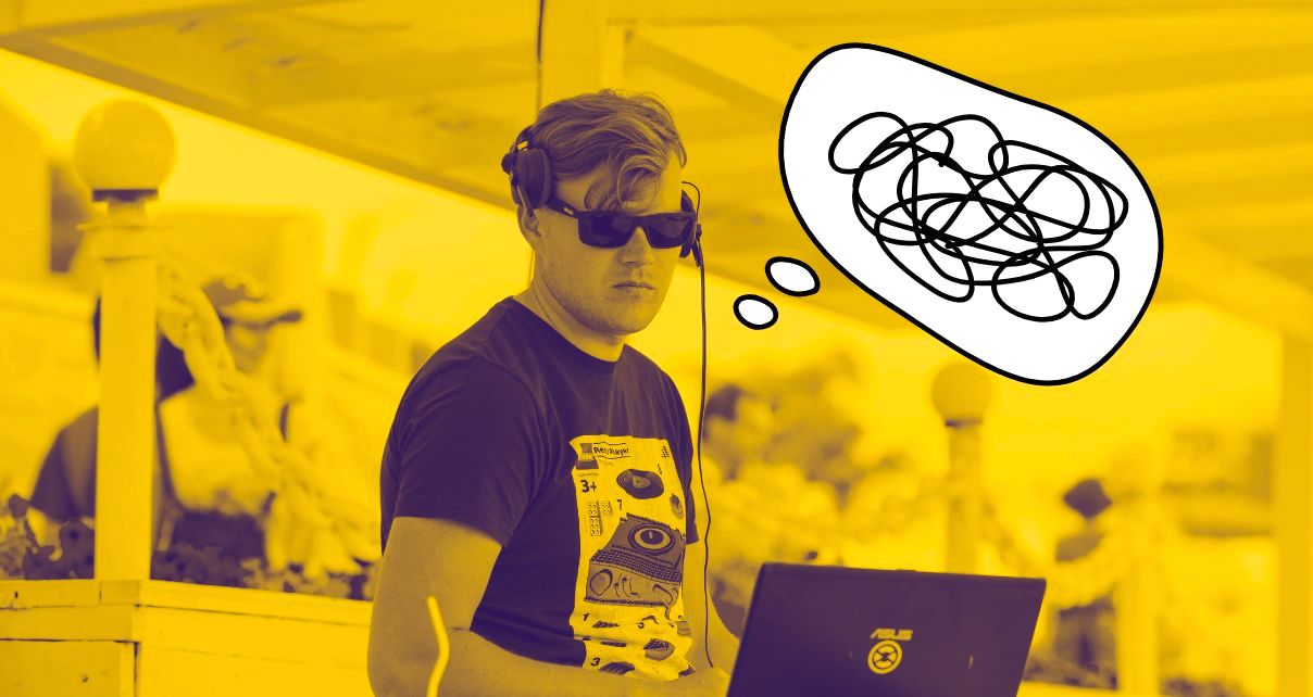 Photo of a tall white man standing behind a laptop. He has short hair and is wearing headphones, a dark t-shirt and sunglasses. The photo is saturated with a yellow colour. Next to his head there is a comic-style thought bubble. Inside the bubble is a bunch of squiggly lines, indicating confusion.