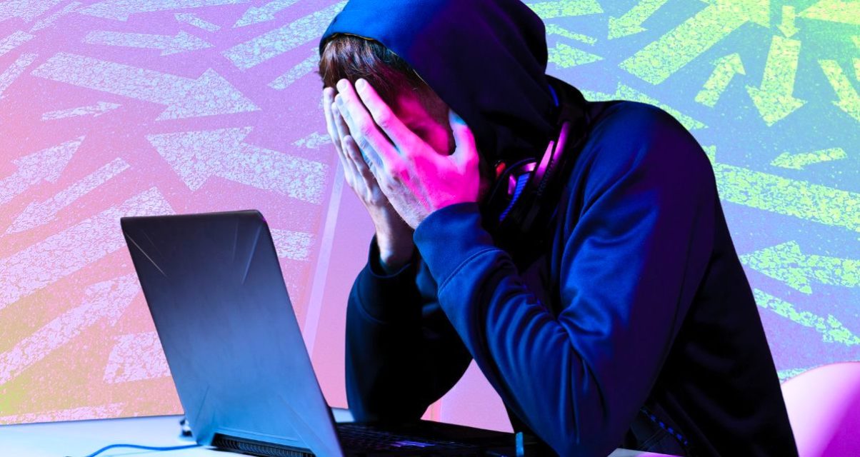 A composite image. In the foreground is a cutout of a younger white person sitting in front of their grey laptop with their head in their hands. They are wearing a shiny midnight blue hoodie with the hood covering their short brunette hair. Around their neck is a pair of headphones. The lighting in the room reflects off their hands and face in pink and blue hues. The background image is a semi-transparent rainbow gradient depicting a straight road down the middle. On each side of the road you can see a variety of arrows pointing in all different directions.