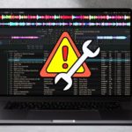 A laptop displaying Mixxx DJ software against a concrete background. There's a yellow, orange, and red warning sign indicating a troubleshooting issue.