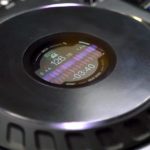 Close-up of a black Pioneer DJ DDJ-FLX10 on-jogwheel display, featuring Djay Pro's colourful waveforms plus tempo and track time indicators.