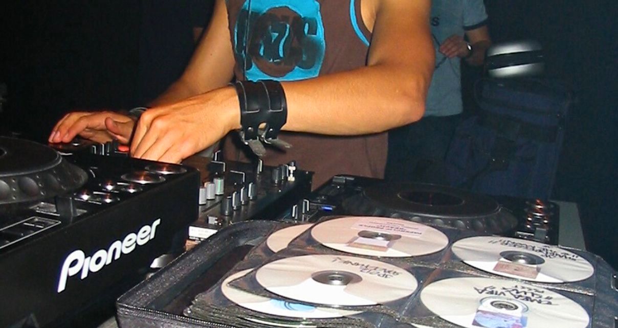 Laidback Luke mixes music on a Pioneer DJ CDJ. On the table next to him is an open CD wallet.