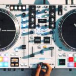 Overhead view of a white Rane One MkII DJ controller. A person is cutting and scratching on the jogwheel and crossfader.