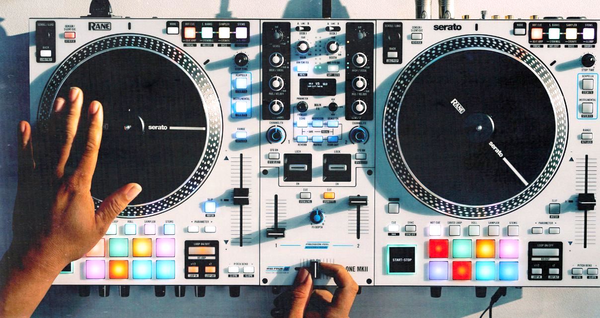Overhead view of a white Rane One MkII DJ controller. A person is cutting and scratching on the jogwheel and crossfader.