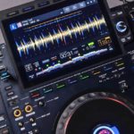 Close-up of an AlphaTheta CDJ-3000x media player featuring dual screens displaying waveforms, track info, and various control buttons for mixing.