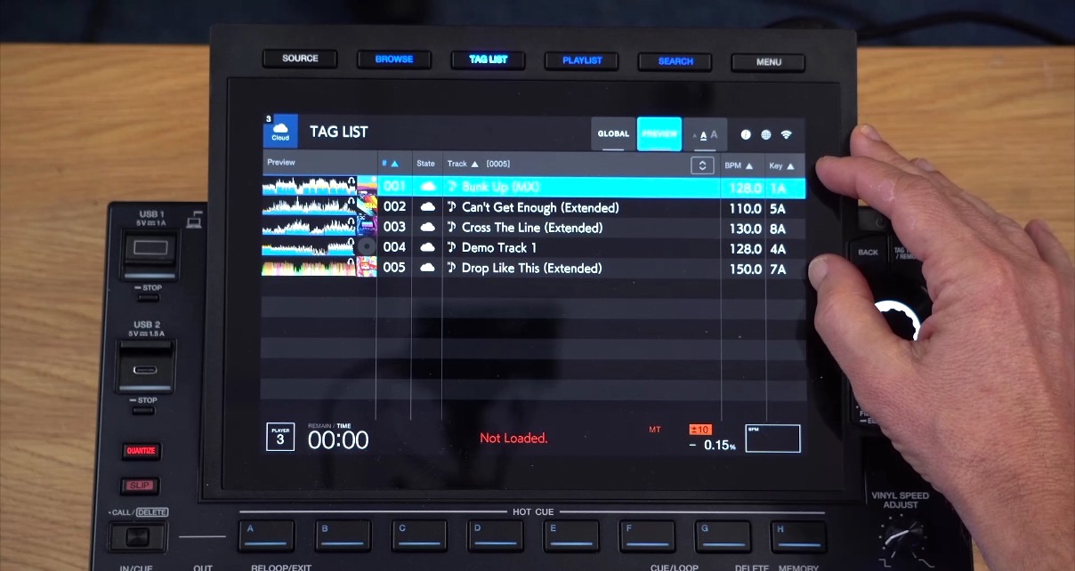 Close-up on a CDJ-3000X screen. A person is gesturing towards the screen, which is displaying the Tag List section. 