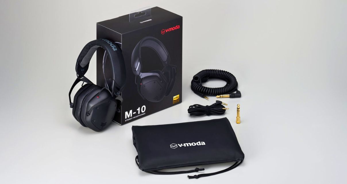 V-MODA M-10 DJ headphones with packaging, coiled and straight cables, a 1/4" adapter, and a carrying pouch on a neutral backdrop.