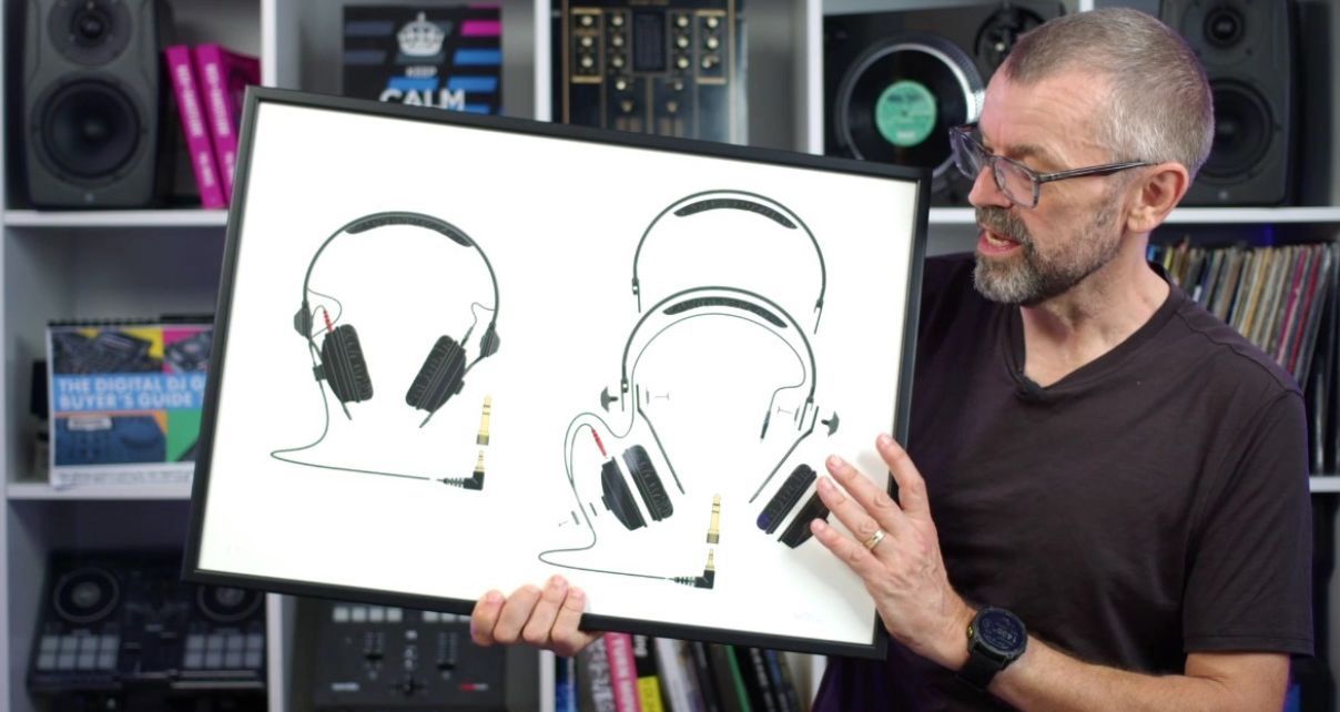 DJ tutor Phil Morse holds a framed illustration of Sennheiser HD-25 headphones with detailed schematic drawings against a white background. Behind him is a large white bookshelf containing various DJ gear, books, and trinkets.
