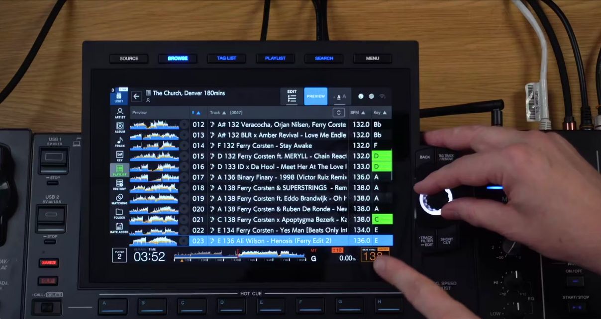 A DJ cycles through their music collection on a CDJ, pointing at the BPM section.