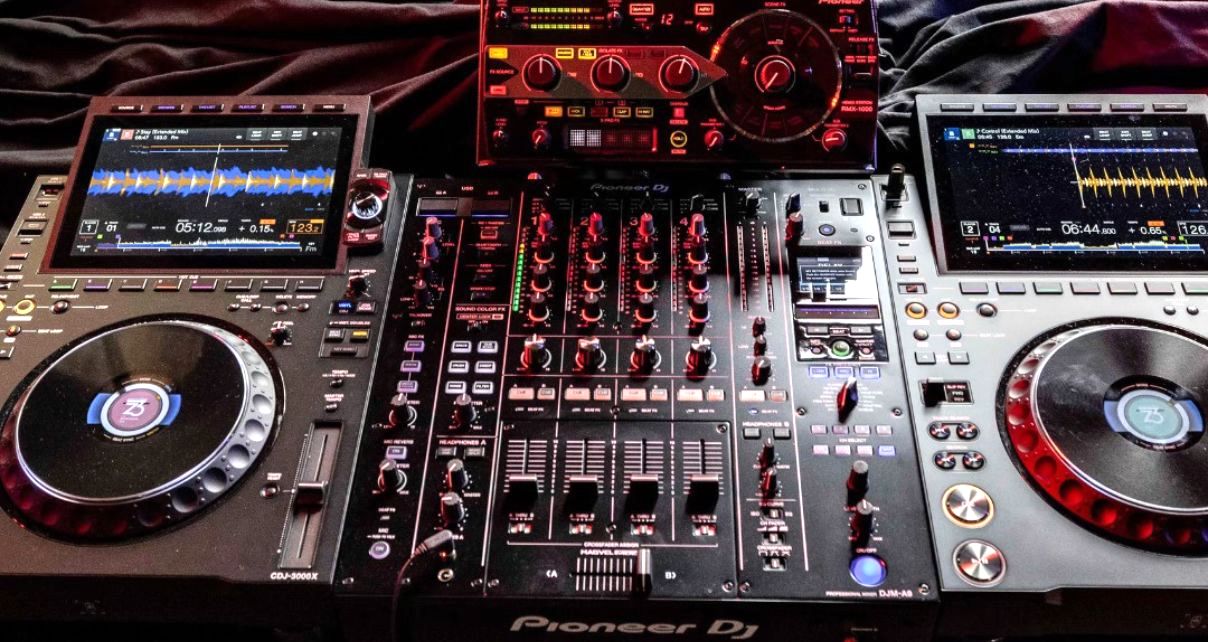 Top-down view of two CDJ-3000X players, an RMX-1000 unit, and a DJM-A9 mixer set up on a desk. 