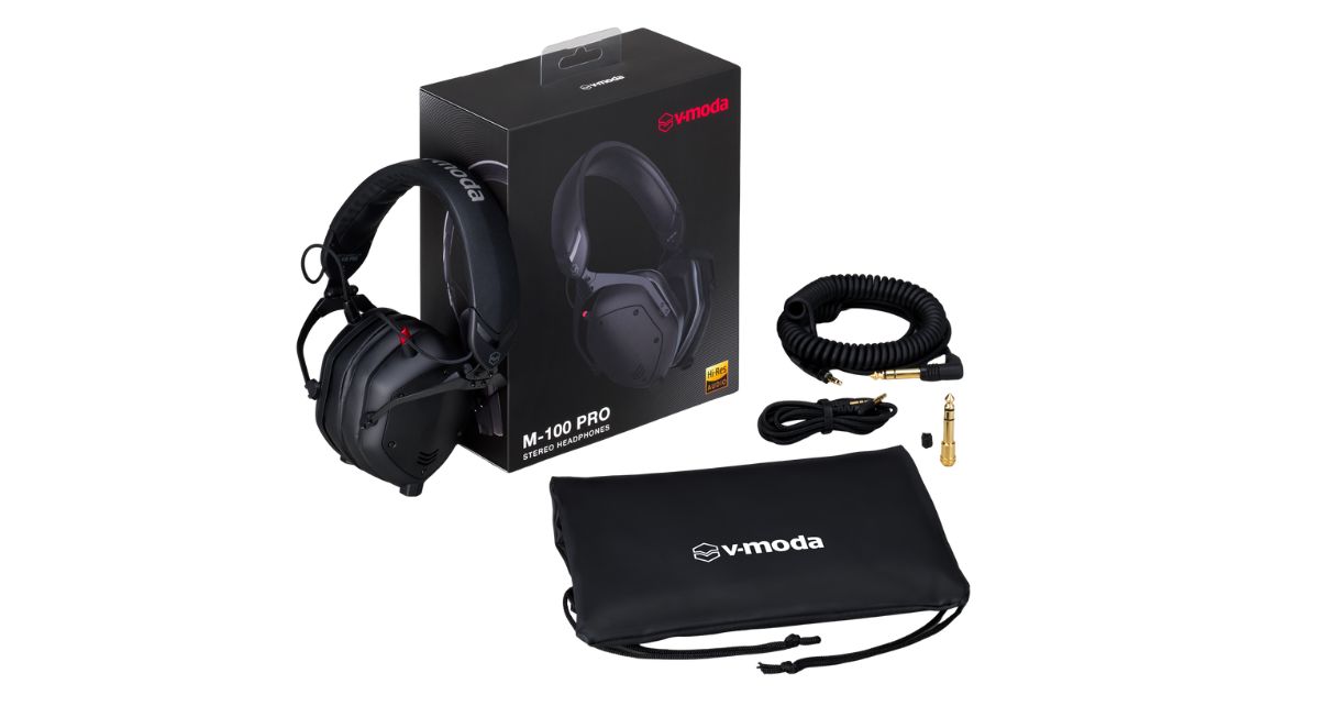 V-MODA M-100 Pro DJ headphones with packaging, coiled and straight cables, a 1/4" adapter, a spare port cover, and a carrying pouch on a white backdrop.
