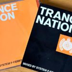 Orange, black and white Trance Nation CD and sleeve side by side on a light wooden desk.