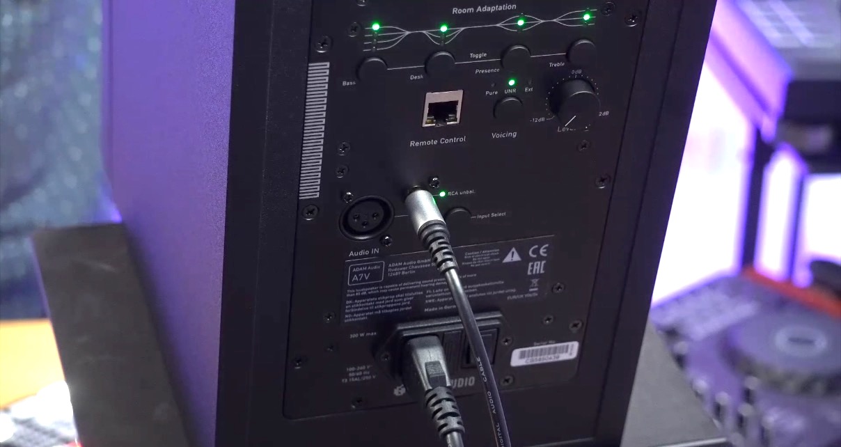 Back view of an Adam Audio A7V monitor showing connection ports, control knobs, and indicators for bass, treble, and remote control settings. 