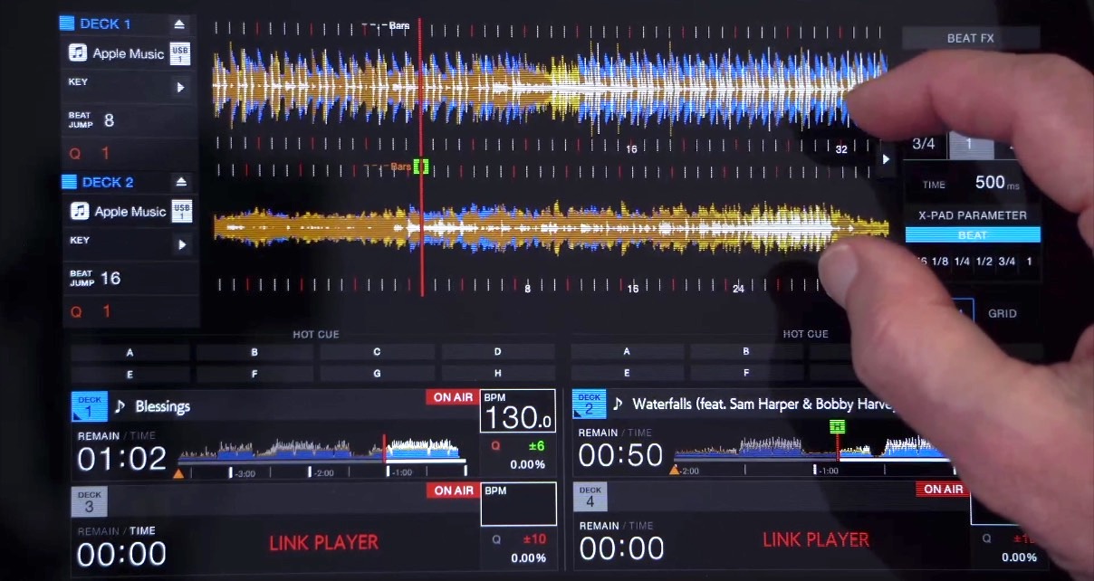 Zoomed-in view of the XDJ-AZ display screen, with a person's hand off to the right gesturing towards two colourful waveforms.