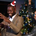 6 Tips To Survive DJing Holiday Parties Three people dance and laugh in front of a Christmas tree. One is wearing a tiny santa hat and another is wearing heart sunglasses with unicorns on it.