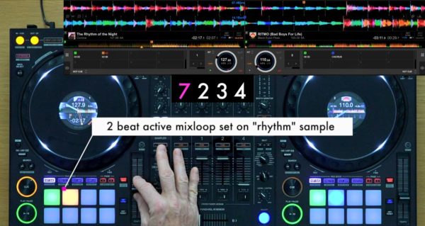 Top-down view of someone mixing on a DJ controller. At the top of the screen is a DJ software visual overlay. The two tracks loaded are Corona's "Rhythm of the Night" and Black Eyed Peas' "Ritmo". The black and white annotation on screen says "2 beat active mixloop set on 'rhythm' sample". 