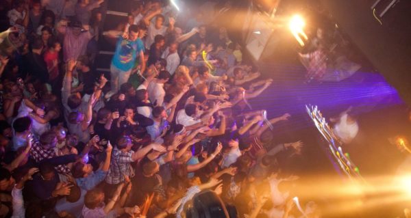 A large, vibrant club crowd gets lost in the music. 