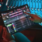 Djay Pro 5.6 Brings Mobile Spotify Integration & Better Hardware Support A person sitting at a mixing desk in a recording studio uses Djay Pro with Spotify on a tablet.