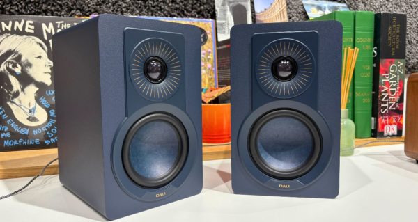 A pair of DALI hi-fi speakers on a bookshelf in a well-lit room. 