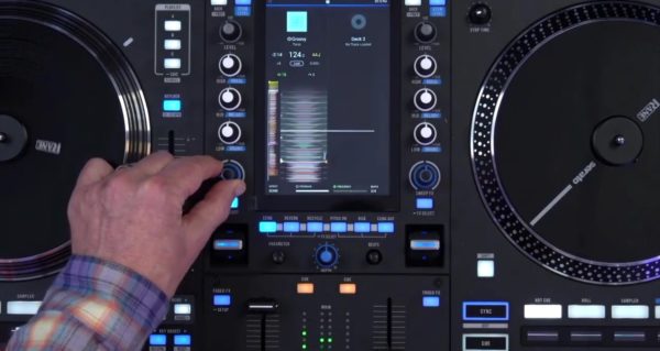 Hand adjusting the sweep effect knob on the Rane System One while the vertical screen displays RGB waveforms. Main effects buttons are visible below the screen showing echo, reverb, and other effect options.