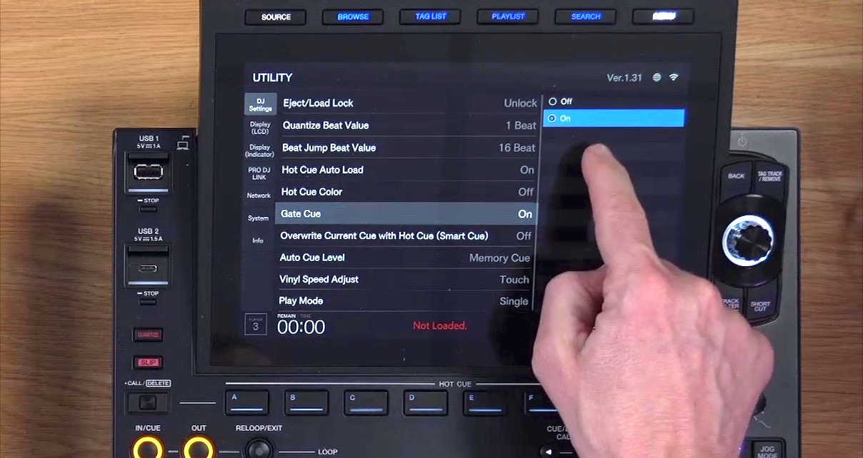 Hand pointing to the Gate Cue setting toggled to "On" in the CDJ-3000X utility menu, showing various other settings including Hot Cue Auto Load, Hot Cue Color, and Auto Cue Level.