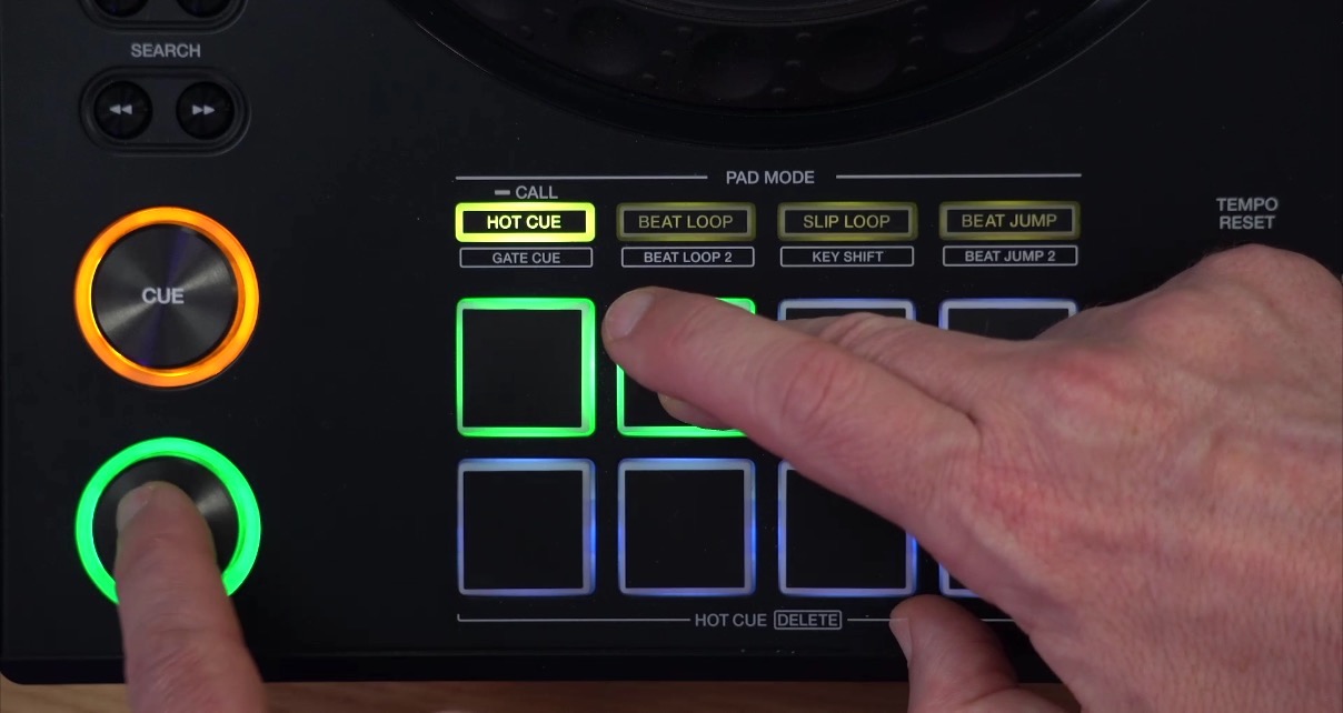A person demonstrating a workaround on an XDJ-AZ by holding down a hot cue pad with their right hand while their left hand presses the green Play button, showing how to make a track continue playing in gated mode.