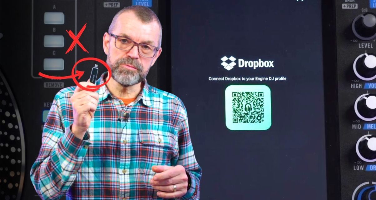 Phil Morse holds up a USB drive with a red X and circle arrow graphic overlaid, standing in front of a Rane System One DJ unit and a screen showing the Dropbox Engine DJ profile connection page with a QR code.