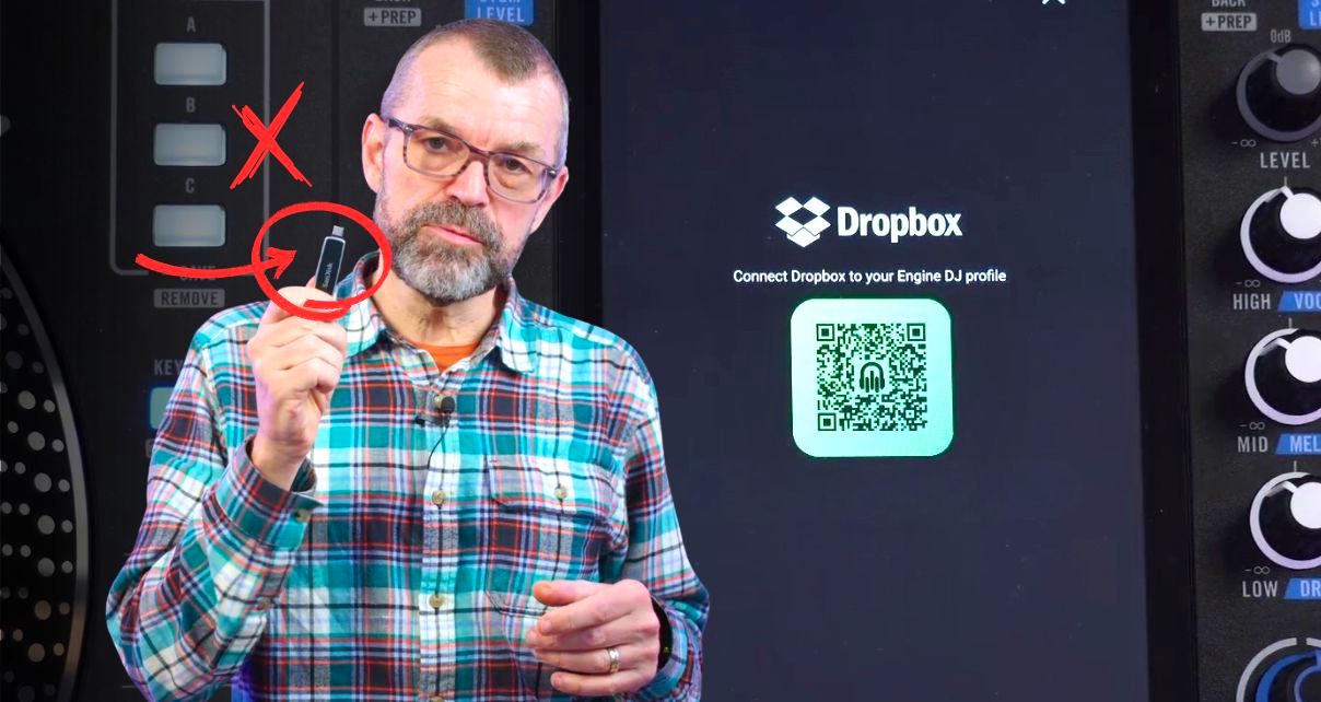 Phil Morse holds up a USB drive with a red X and circle arrow graphic overlaid, standing in front of a Rane System One DJ unit and a screen showing the Dropbox Engine DJ profile connection page with a QR code.