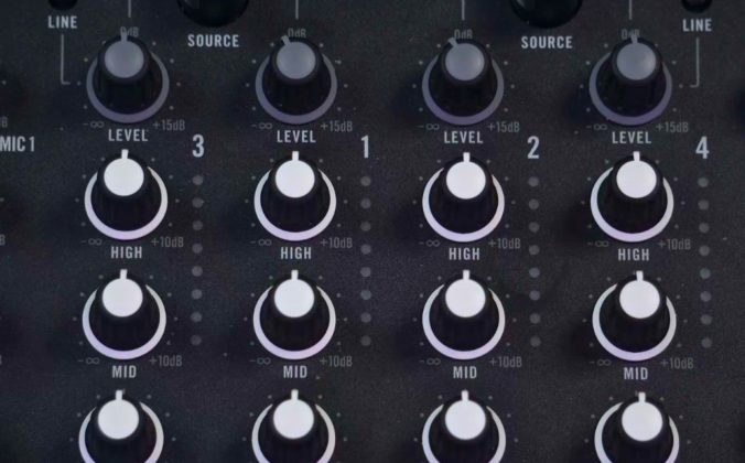 Close-up of a DJ mixer showing four channel level/gain controls at the top, with high, mid and low EQ knobs below on each channel.