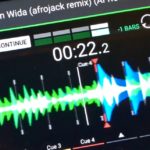 A close-up of an Engine DJ software screen showing the waveform of Skrillex's Agen Wida (Afrojack Remix) at 128 BPM, with cue points marked and a dense, blue and green waveform visible.