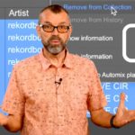 Phil Morse stands in front of a large screen showing a Rekordbox library with drum loop samples selected, with a right-click context menu open showing "Remove from Collection" highlighted. A circular arrow icon to his right suggests the loops keep returning. Phil is wearing a salmon pink short-sleeved shirt with a small repeating pattern, and has his hands raised with palms up in a "what can you do?" gesture.